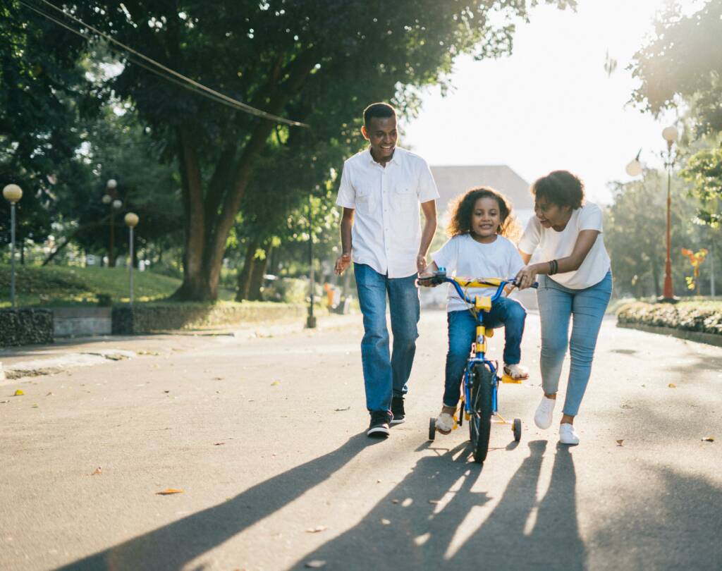 parents teaching their daughter to bike